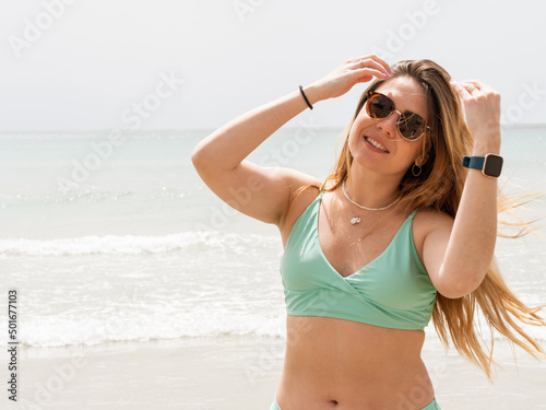 woman on the beach with sunglasses and the sea on the background
