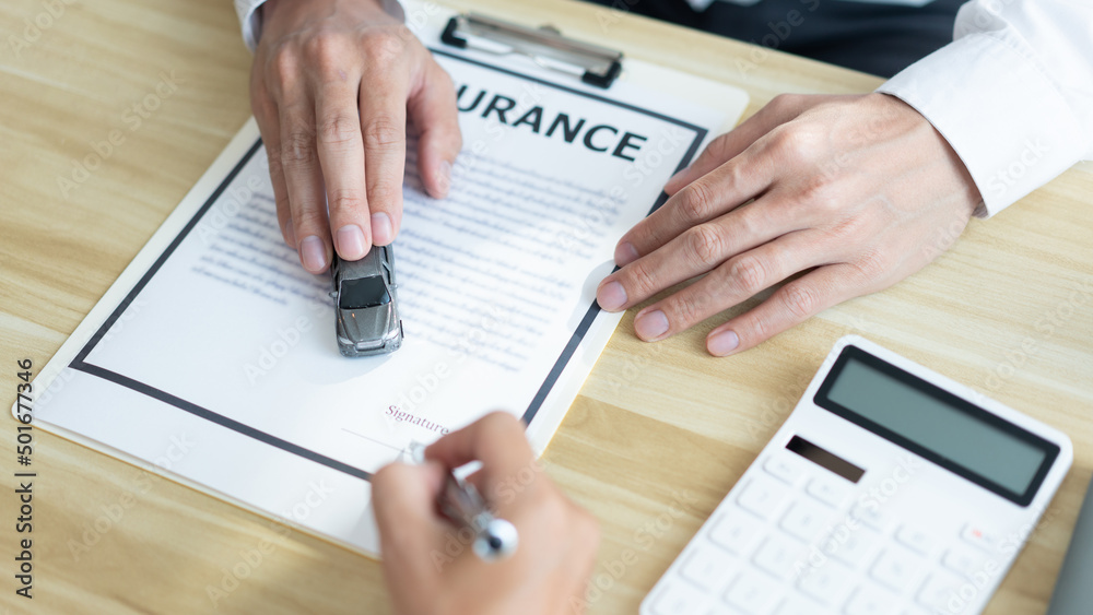 Insurance concept the customer signing his name on the contract while the dealer giving more details Insurance concept the customer signing his name on the contract while the dealer giving more details