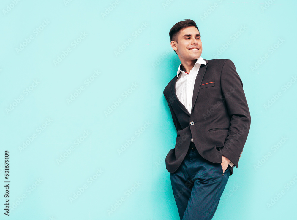 Portrait of handsome confident stylish hipster lambersexual model. Sexy modern man dressed in elegant black suit. Fashion male isolated on blue Portrait of handsome confident stylish hipster lambersexual model. Sexy modern man dressed in elegant black suit. Fashion male isolated on blue