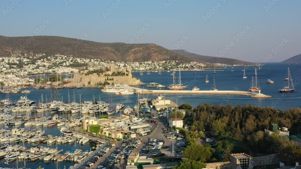 aerial drone flying up revealing Bodrum Castle in the distance during a sunny summer afternoon in the Aegean Sea as the sun sets over the mountains aerial drone flying up revealing Bodrum Castle in the distance during a sunny summer afternoon in the Aegean Sea as the sun sets over the mountains