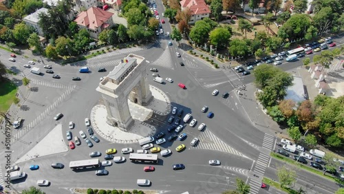overhead aerial video of Arc de Triomphe in Bucharest from above, arc de triumf in romania, parc drone view from above with cars driving by on a sunny summer day with green trees dolly zoom photo