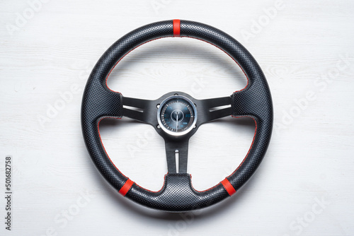 Sport car steering wheel and boost pressure sensor on the white flat lay table background.