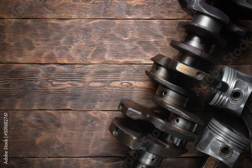 Old car crankshaft and engine pistons on the wooden workbench flat lay background with copy space. photo