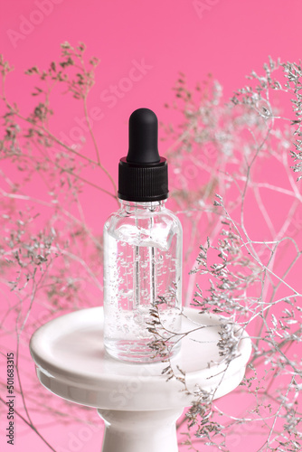 Cosmetic glass bottle with dropper on podium. The concept of a beauty salon and natural cosmetics.