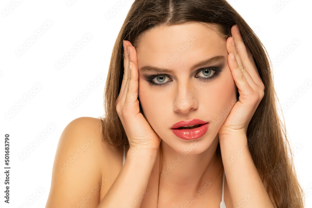 Young woman tightening her face skin with her palms on a white background Young woman tightening her face skin with her palms on a white background