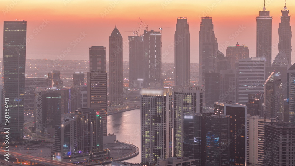 Skyline with modern architecture of Dubai business bay towers day to night timelapse. Aerial view