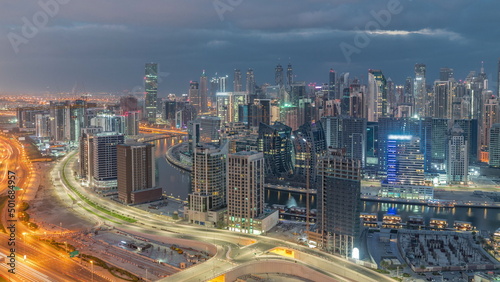Skyline with modern architecture of Dubai business bay towers night to day timelapse. Aerial view