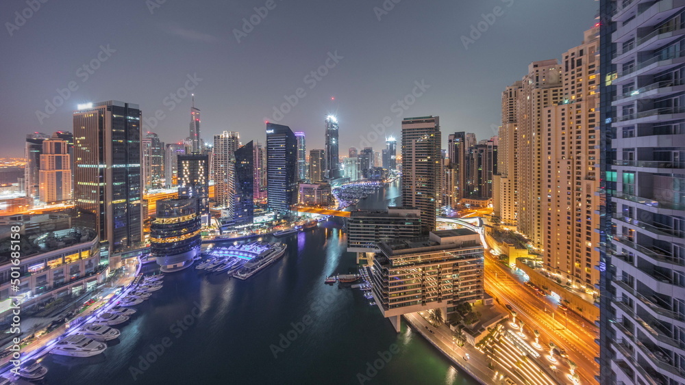 Naklejka premium Aerial view to Dubai marina skyscrapers around canal with floating boats night to day timelapse