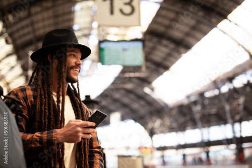 Handsome guy at railway station waiting for the train. Young man waiting to board a train. Urban guy using the phone photo