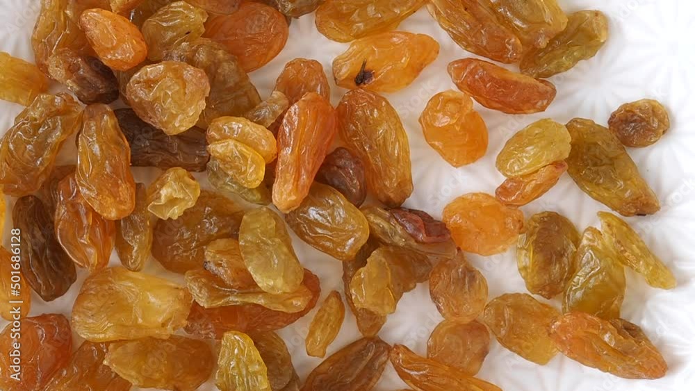Raisins dried white grapes pour on a plate. Large dry raisin berries in motion, Raisins dried white grapes pour on a plate. Large dry raisin berries in motion,