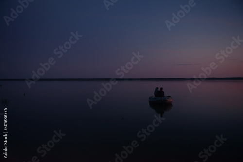 Father and son go to night fishing in a boat. Night fishing on the lake. Leisure, joint pastime of his son with his father, a common hobby. The concept of fishing, tourism and rest