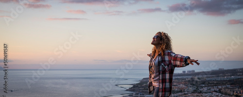 Obraz na plátně Happy woman outstretching arms with sunset on the ocean coast in background