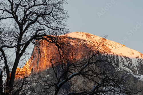 Telephoto shot of a snowy half dome catching the last rays of sunlight on a winter evening.