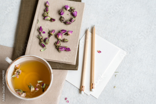 The word "love" laid out with dry rose flowers on the top of the notepad.