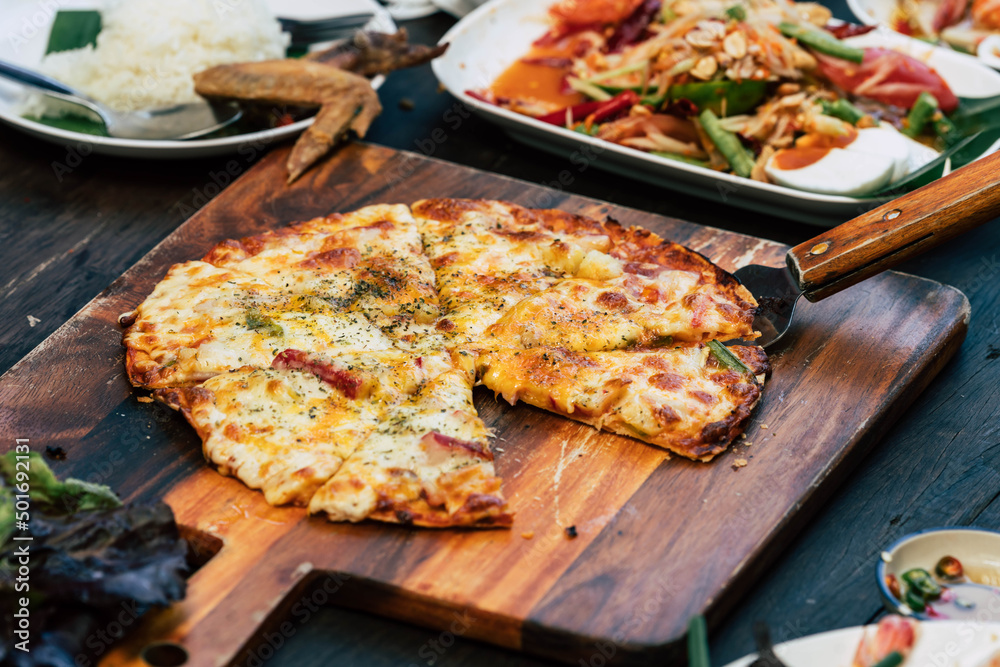 Homemade pizza with spicy Asian food on wood table