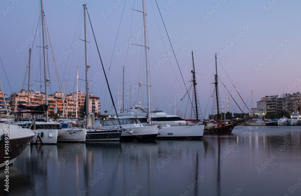 Marine theme, sail boats, yachts on the pier, reflection on the water, in the evening, summer day in Greece