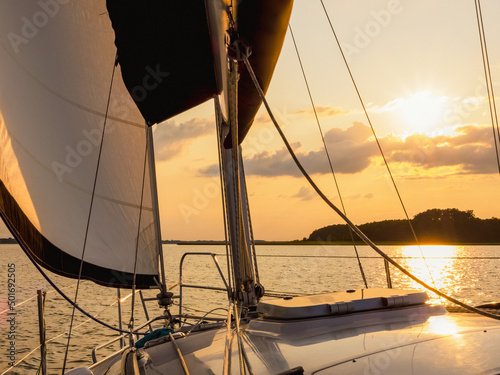 sailing yacht bow in sunset light, sailing on a lake © lenaivanova2311
