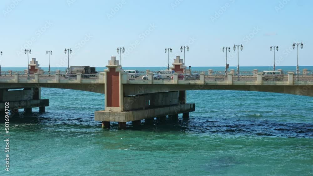 Stanley Bridge on waterfront promenade corniche in Alexandria. Cars driving over architectural construction in Mediterranean sea with beautiful towers, street lamps in Egyptian city Stanley Bridge on waterfront promenade corniche in Alexandria. Cars driving over architectural construction in Mediterranean sea with beautiful towers, street lamps in Egyptian city