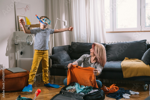 mother and son having great time while packing bags for summer vacation