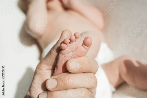 Baby feet. The father holds with tenderness and love in his hands the small legs of a newborn. New life, parental protection, care, love, child and baby health
