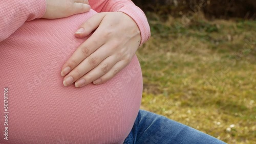 Wallpaper Mural Pregnant woman sits on a park bench and strokes her belly. Pregnancy and carrying a baby. Torontodigital.ca