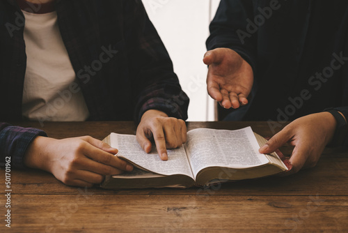 Two christianity sitting around wooden table with open holy bible study reading together in Sunday school. Christian bible god deliver devotional with hand friendship.
