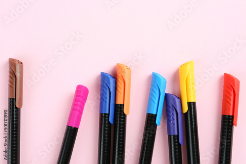 Many colorful markers on pink background, flat lay with space for text. School stationery