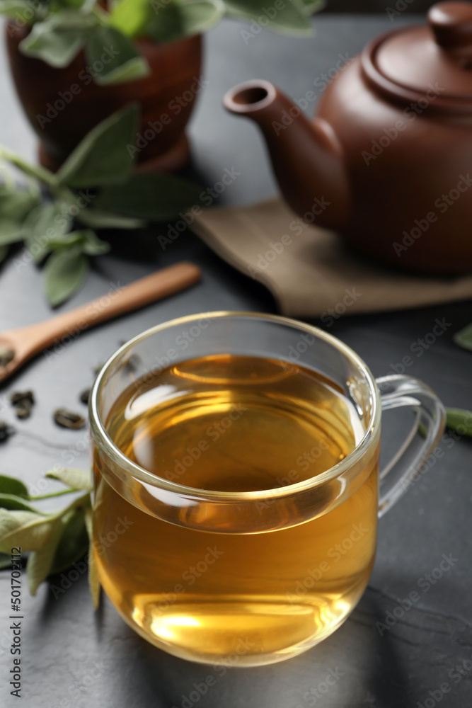 Cup of aromatic sage tea on black table. Space for text Cup of aromatic sage tea on black table. Space for text