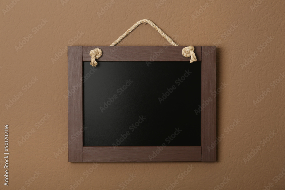 Clean small black chalkboard hanging on brown wall Clean small black chalkboard hanging on brown wall
