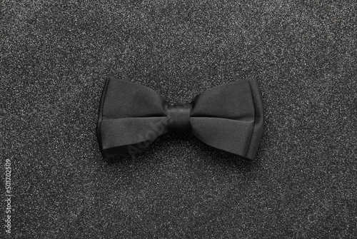 Foto Stylish black bow tie on dark stone background, top view