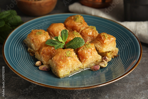 Delicious baklava with pistachio nuts and mint on grey table