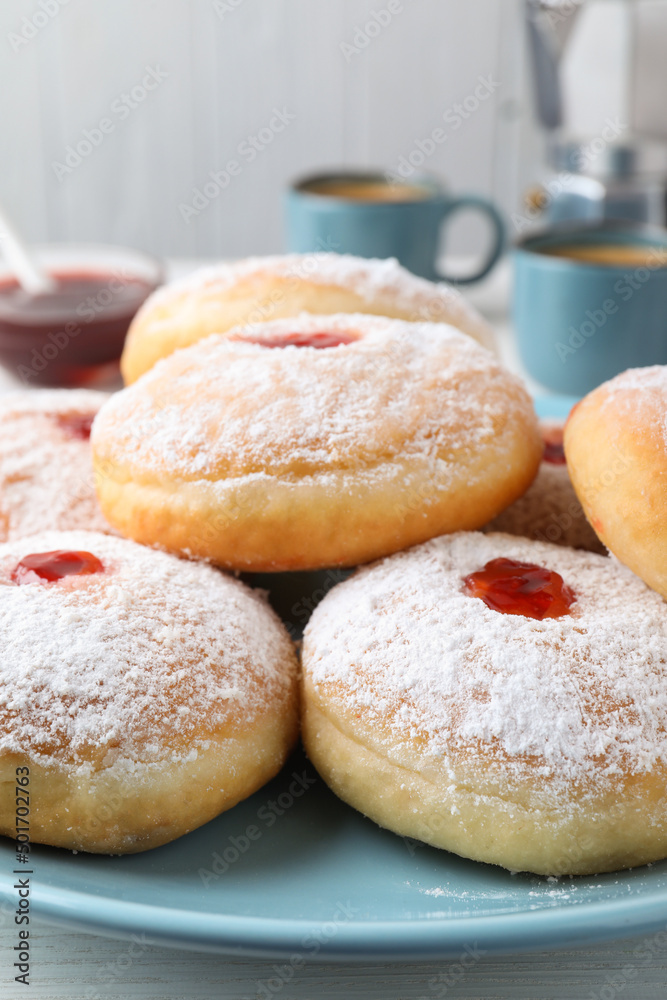 Delicious donuts with jam and powdered sugar on blue plate, closeup