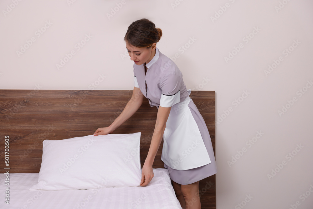 Beautiful chambermaid making bed in hotel room Beautiful chambermaid making bed in hotel room