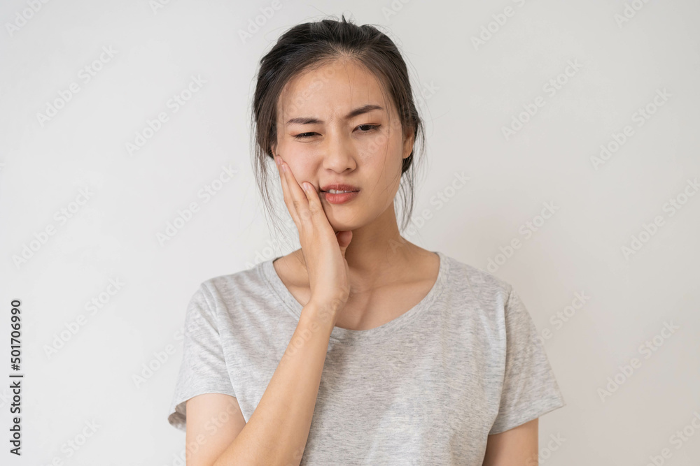 Closing eyes asian young woman touching cheek, face expression from toothache, tooth decay or sensitivity, Having tooth or teeth problem or inflammation, suffering from health. Sensitive teeth people Closing eyes asian young woman touching cheek, face expression from toothache, tooth decay or sensitivity, Having tooth or teeth problem or inflammation, suffering from health. Sensitive teeth people
