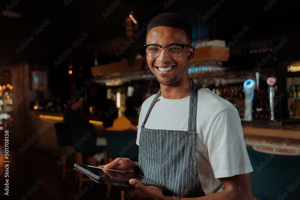 African American male waiter smiling holding digital tablet
