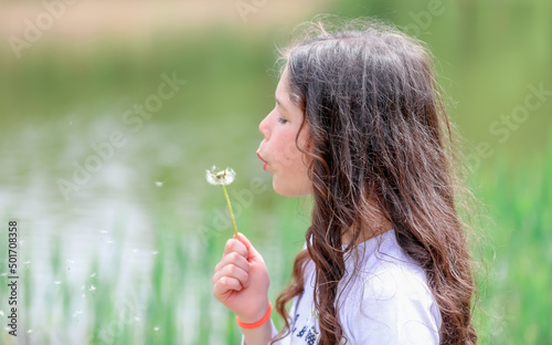 girl blowing dandelion in the garden