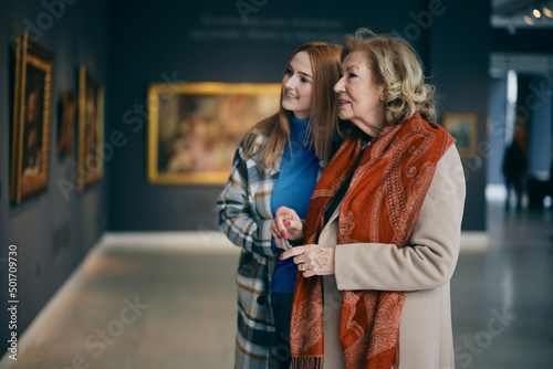 Fotografia Grandmother and adolescent granddaughter are looking at the paintings in the art gallery
