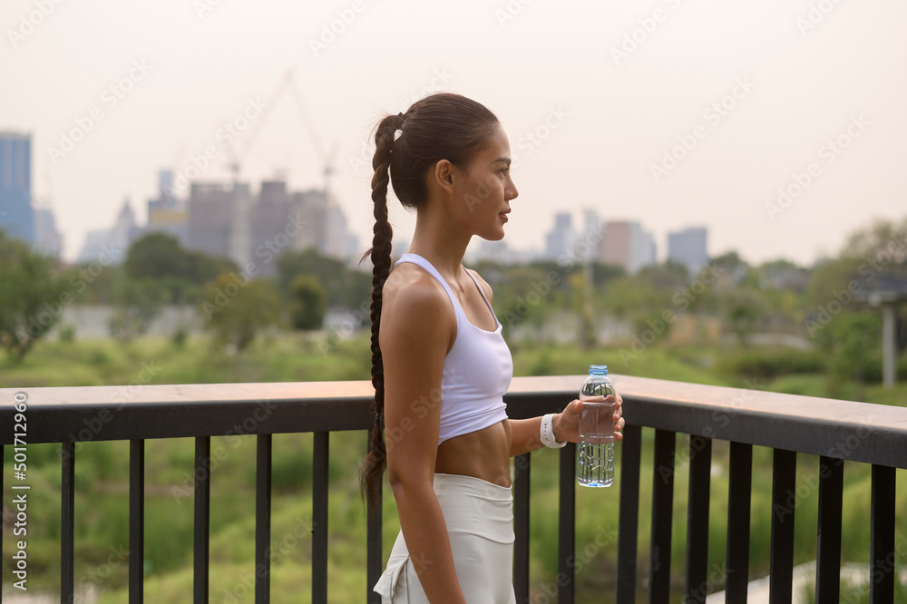 Young fitness woman in sportswear drinking water in city park, Healthy and Lifestyles.