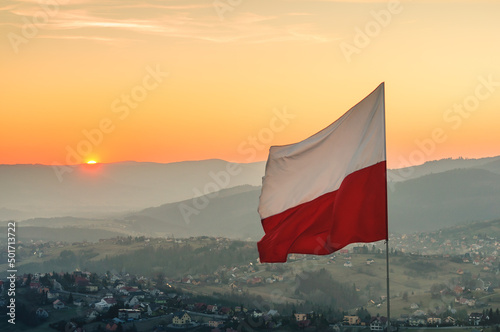 Biało-czerwona flaga Polski na tle zachodzącego słońca w górach - Ochodzita, Koniaków © charlottemelanie