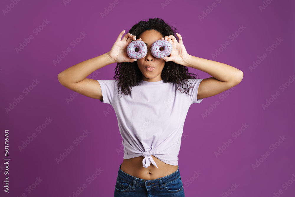 Young black woman wearing t-shirt making fun with donuts Young black woman wearing t-shirt making fun with donuts
