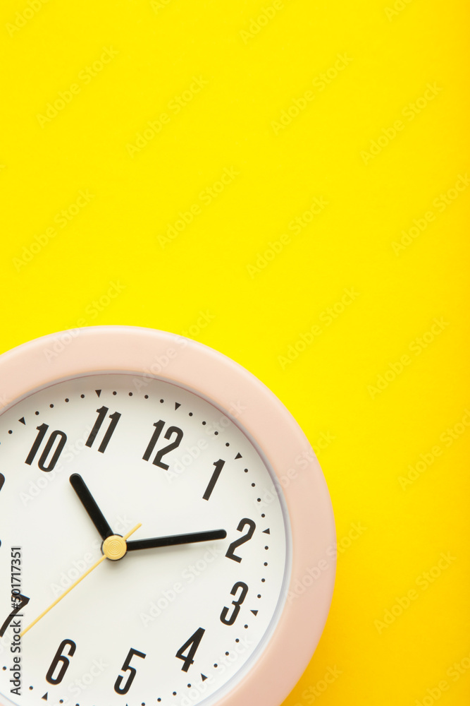 Pink clock on yellow background. Top view.