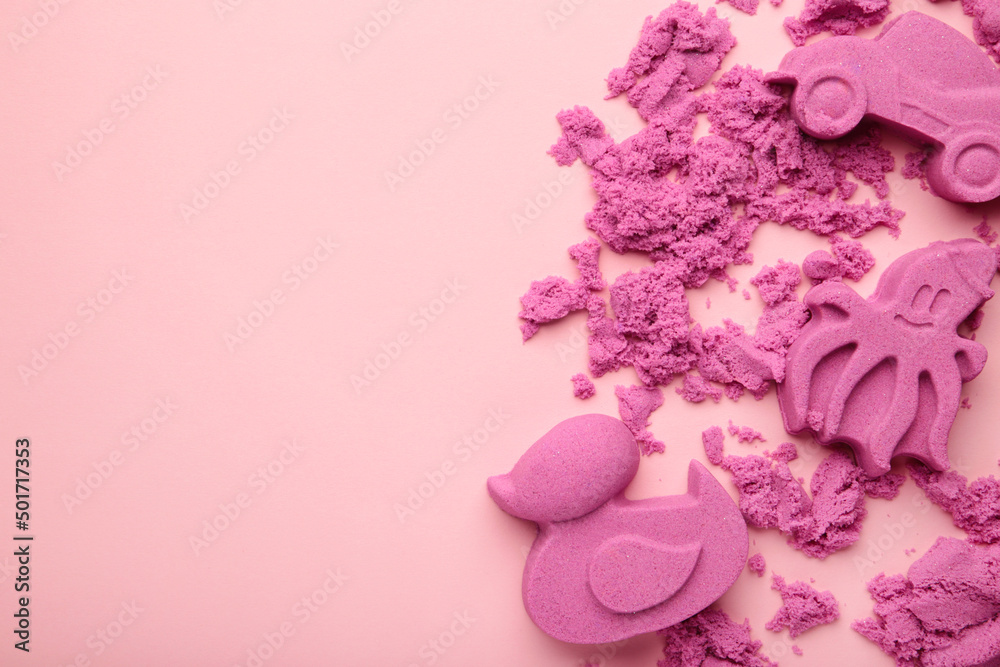 Fototapeta premium Pink kinetic sand for children, development and play at home with multi-colored sandbox molds on pink background.