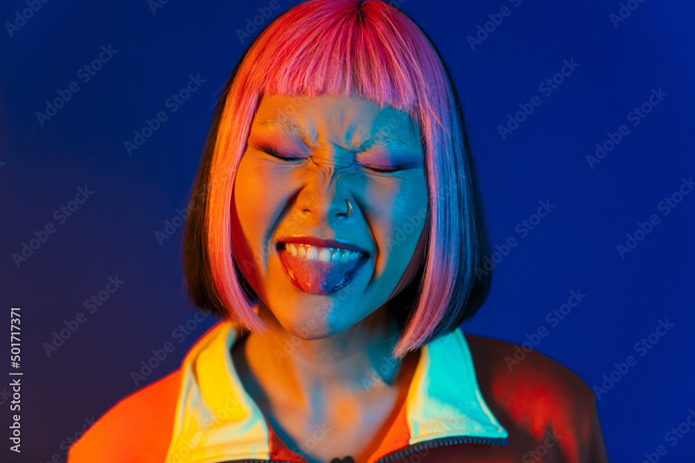 Asian girl with pink hair and piercing showing her tongue Asian girl with pink hair and piercing showing her tongue