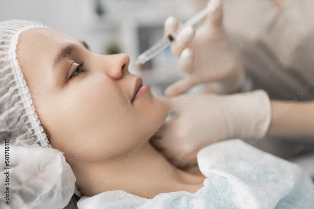 cosmetologist makes an injection at the client's nose. cosmetic wrinkle removal