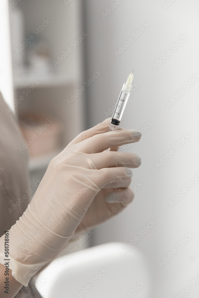 doctor cosmetologist holds in his hand and shows a syringe with a small needle for procedures