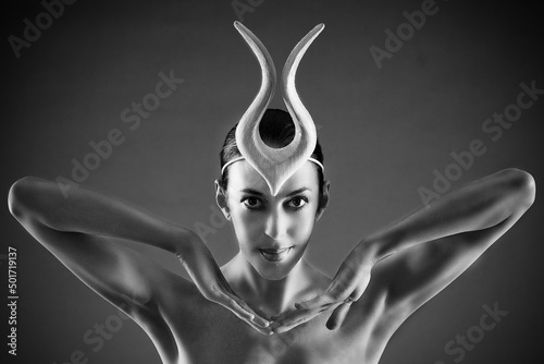 a charming ballerina in a bodysuit poses ballet elements in a headdress in a photo studio photo