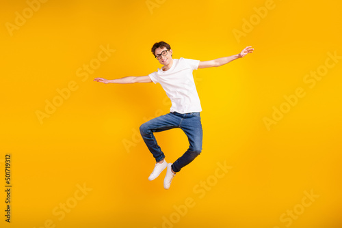 Full body photo of young cheerful man good mood arms wings fly air jumper isolated over yellow color background © Tetiana