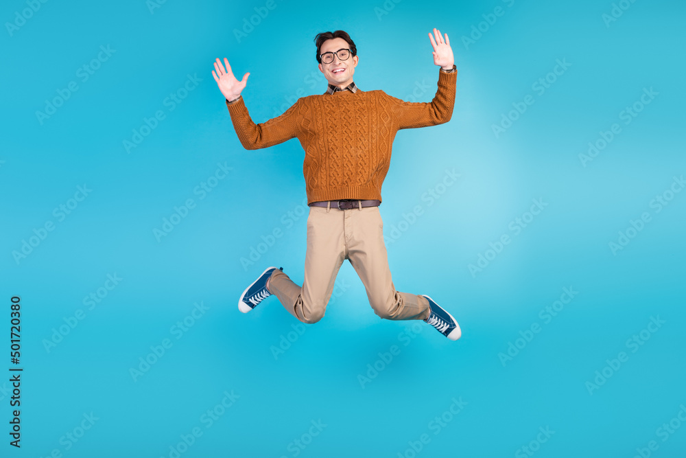 Fototapeta premium Full length photo of young man jump up wave hands hello energetic travel isolated over blue color background