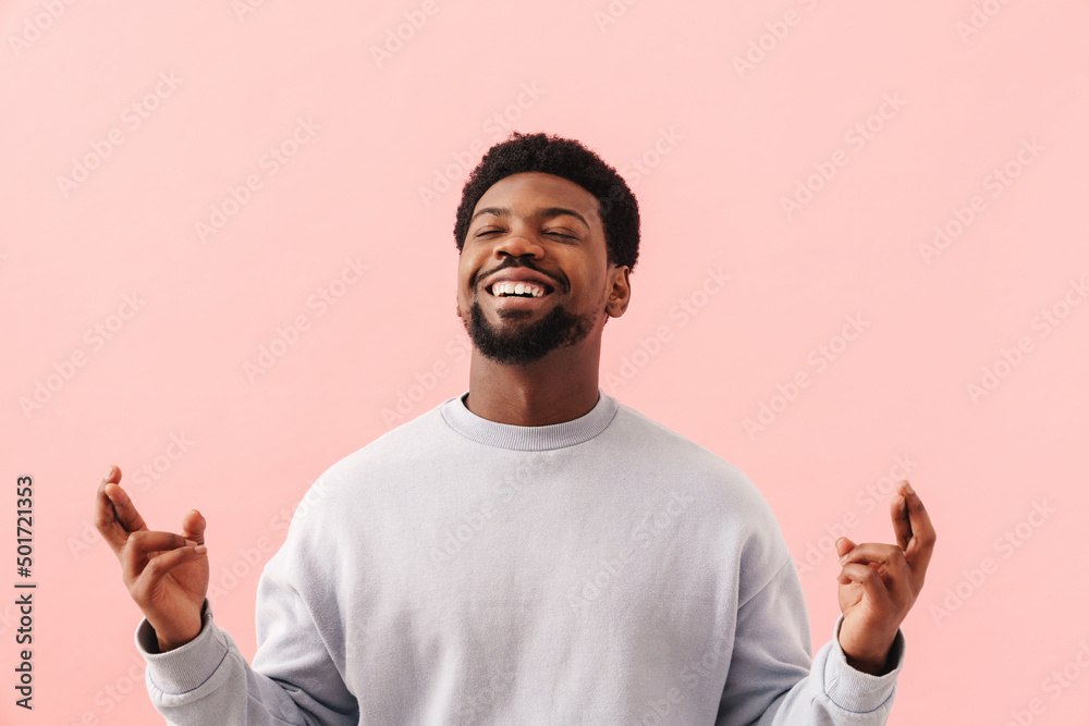 Black mid man smiling and holding fingers crossed for good luck Black mid man smiling and holding fingers crossed for good luck