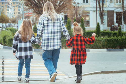 Wallpaper Mural young woman takes two girls across the road in the city. Mom holds her daughters hands and teaches them to cross the road safely at a pedestrian crossing Torontodigital.ca